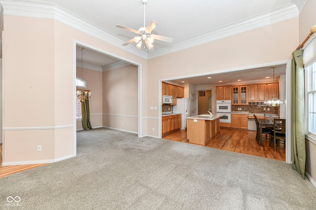 unfurnished living room with light carpet, ceiling fan, and crown molding