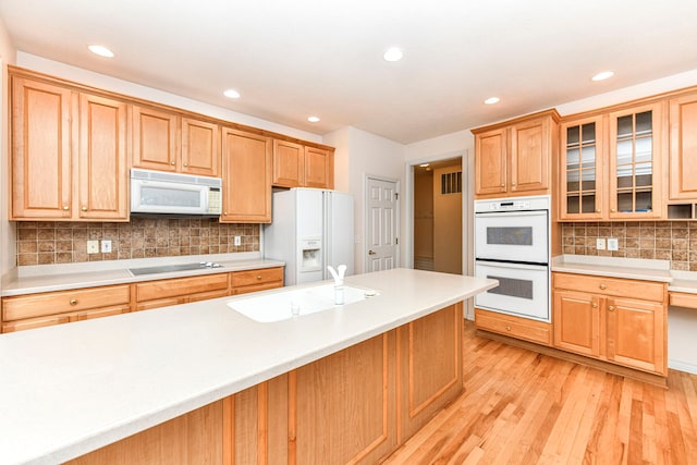 kitchen with backsplash, sink, white appliances, and light hardwood / wood-style floors