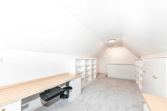 additional living space featuring built in shelves, light carpet, and lofted ceiling