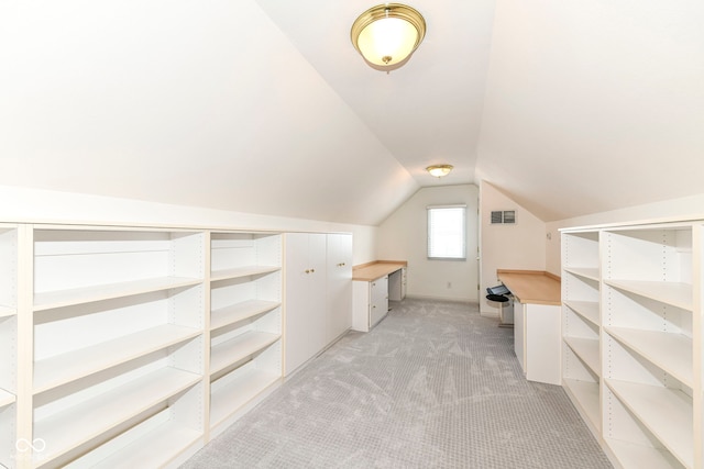 walk in closet with light carpet and lofted ceiling