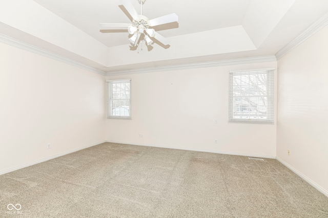 carpeted empty room with a raised ceiling, ceiling fan, and crown molding