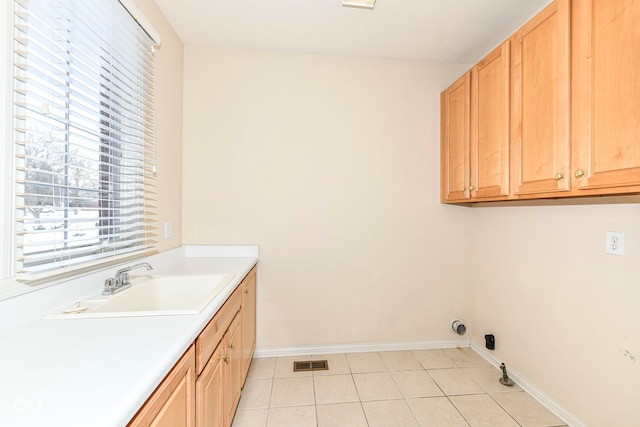 laundry area with light tile patterned floors, sink, and cabinets