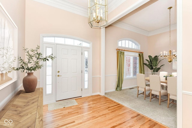 foyer featuring hardwood / wood-style flooring, a wealth of natural light, ornamental molding, and a notable chandelier