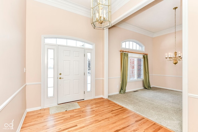 carpeted entryway with crown molding and an inviting chandelier