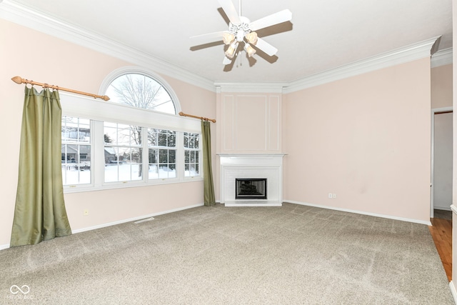 unfurnished living room featuring a large fireplace, crown molding, and carpet floors