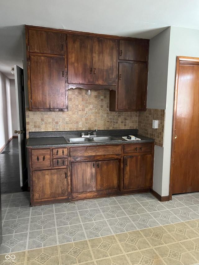 kitchen featuring sink, light tile patterned flooring, decorative backsplash, and dark brown cabinetry