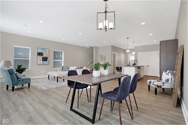 dining area featuring a notable chandelier, light hardwood / wood-style flooring, and sink