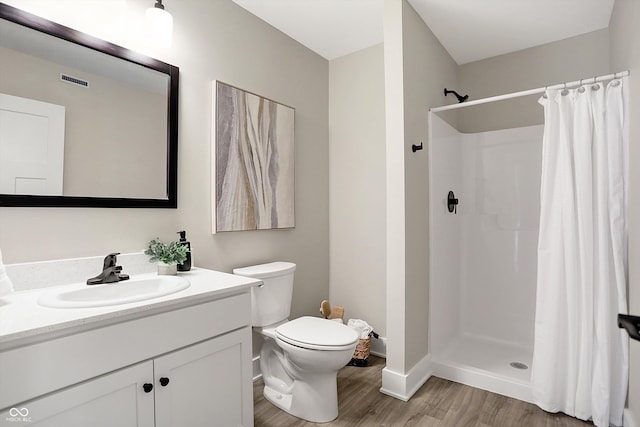 bathroom with wood-type flooring, toilet, vanity, and a shower with curtain