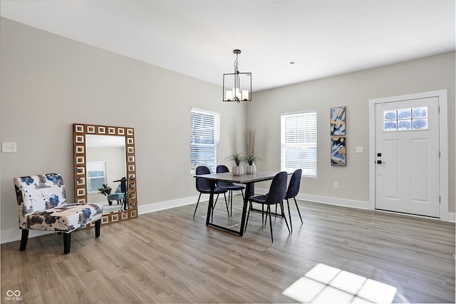 dining space featuring light wood-type flooring and an inviting chandelier