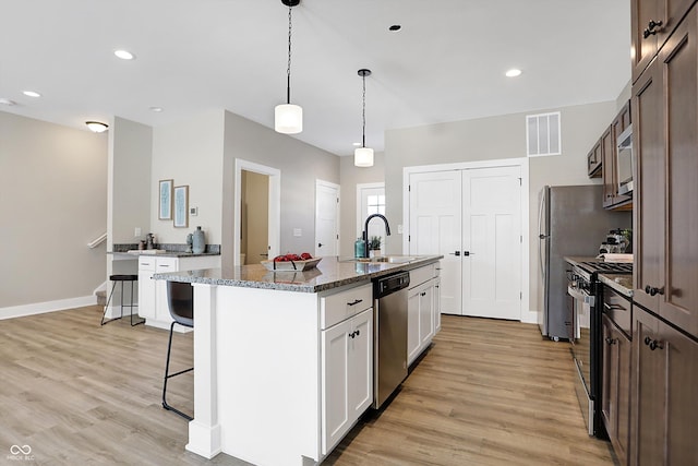 kitchen featuring stainless steel appliances, a center island with sink, white cabinets, and sink