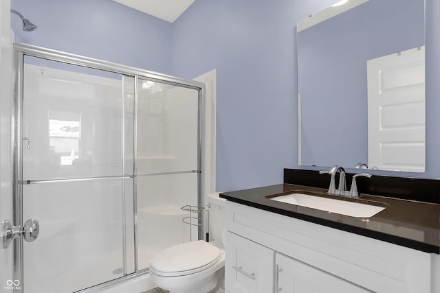 bathroom with toilet, vanity, and a shower with door