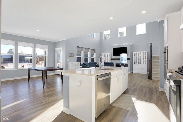 kitchen featuring hardwood / wood-style floors, sink, a kitchen island with sink, stainless steel appliances, and white cabinets