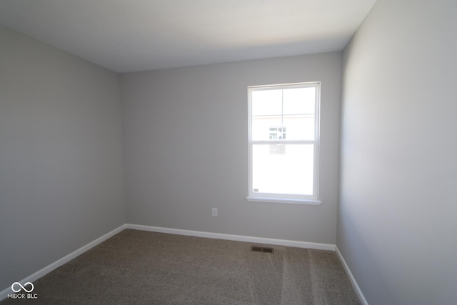 spare room with carpet flooring, visible vents, and baseboards