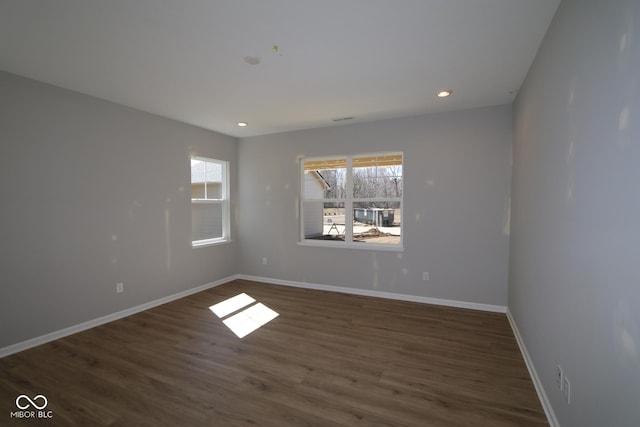 empty room with dark wood-type flooring, recessed lighting, and baseboards