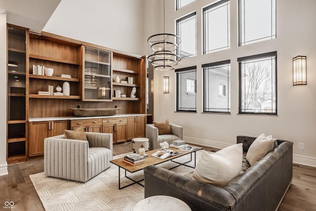 living area featuring light wood-type flooring, a towering ceiling, and a notable chandelier