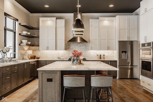 kitchen featuring light stone countertops, white cabinets, appliances with stainless steel finishes, a kitchen island, and decorative backsplash