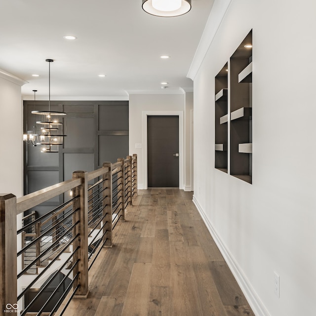 hall with an inviting chandelier, crown molding, and wood-type flooring