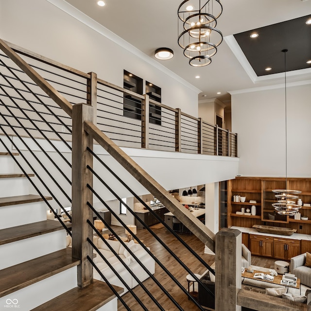 stairway featuring hardwood / wood-style floors, crown molding, and a notable chandelier