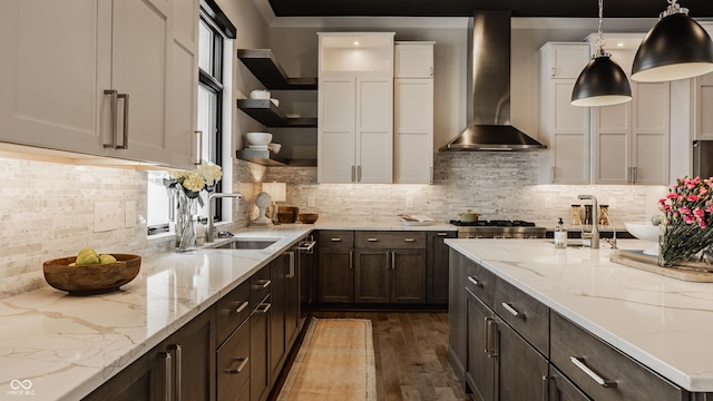 kitchen with white cabinets, wall chimney exhaust hood, sink, backsplash, and light stone counters