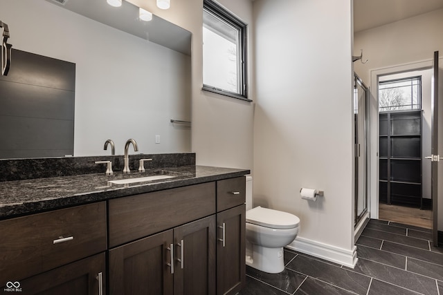 bathroom featuring toilet, an enclosed shower, and vanity