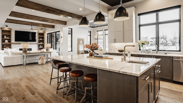 kitchen with white cabinetry, hanging light fixtures, and a kitchen island with sink