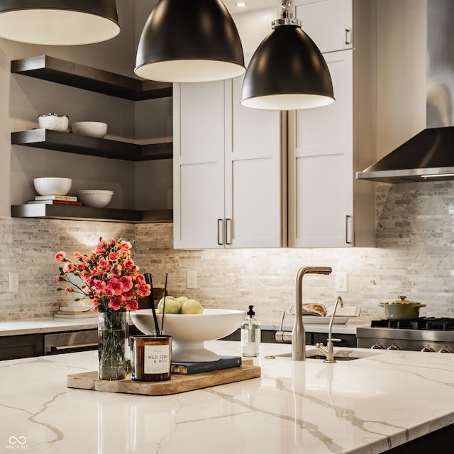 kitchen with decorative backsplash, light stone countertops, white cabinetry, and wall chimney exhaust hood