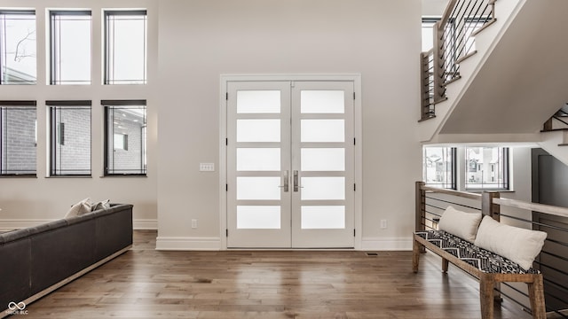 foyer with french doors, a towering ceiling, and hardwood / wood-style floors