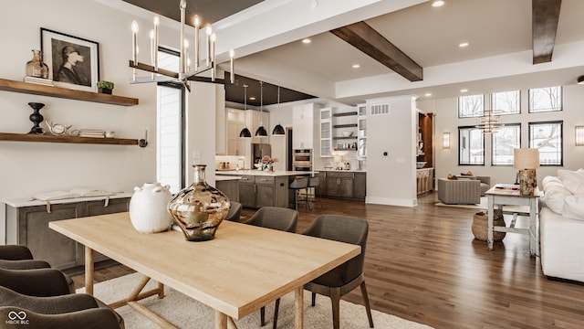 dining space with beam ceiling, dark wood-type flooring, and a chandelier