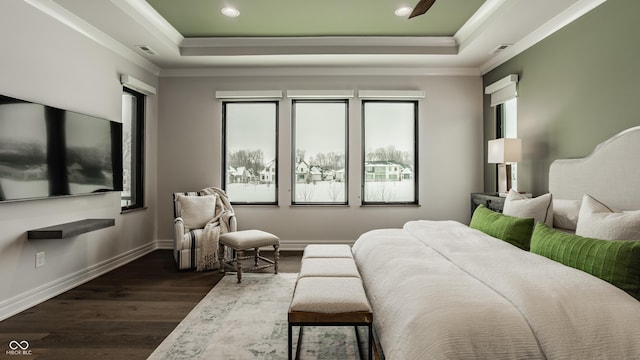 bedroom featuring a raised ceiling, dark hardwood / wood-style floors, multiple windows, and ornamental molding