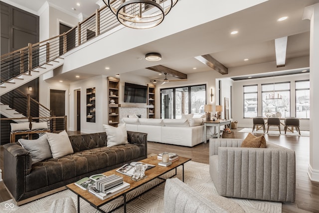 living room with built in features, wood-type flooring, a notable chandelier, and beamed ceiling