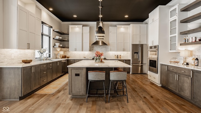 kitchen featuring high quality fridge, white cabinets, light wood-type flooring, and a center island