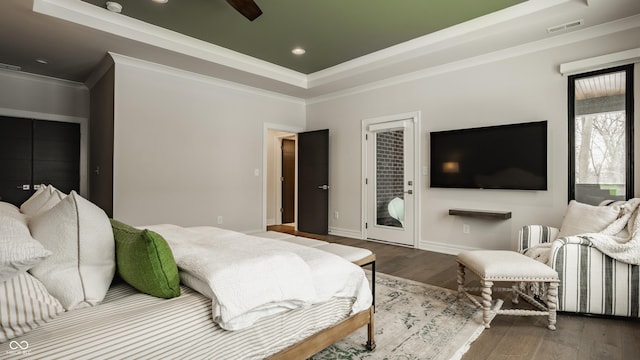 bedroom with ceiling fan, access to exterior, hardwood / wood-style floors, and a tray ceiling