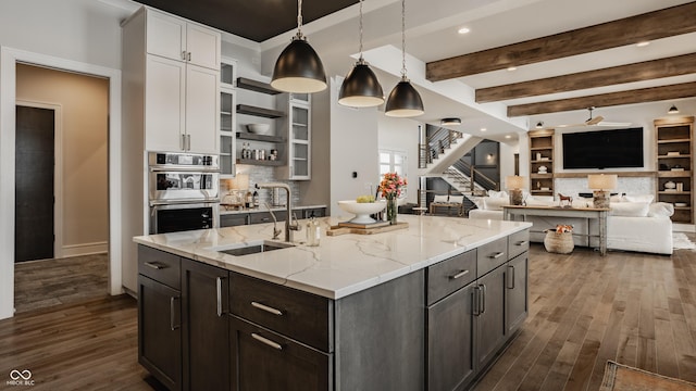 kitchen with beam ceiling, white cabinets, sink, and hanging light fixtures