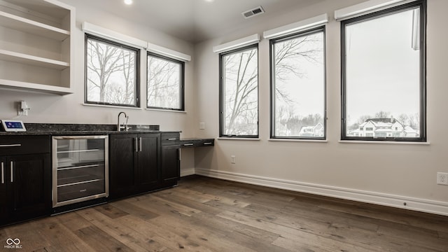 bar featuring sink, dark hardwood / wood-style floors, beverage cooler, and dark stone countertops