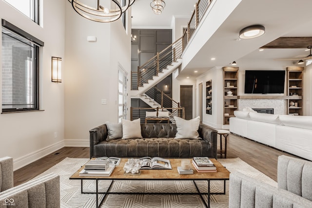 living room with a notable chandelier, beam ceiling, a towering ceiling, a stone fireplace, and dark hardwood / wood-style flooring