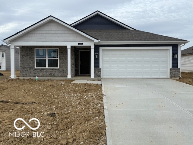 view of front of house with driveway, stone siding, a garage, and roof with shingles