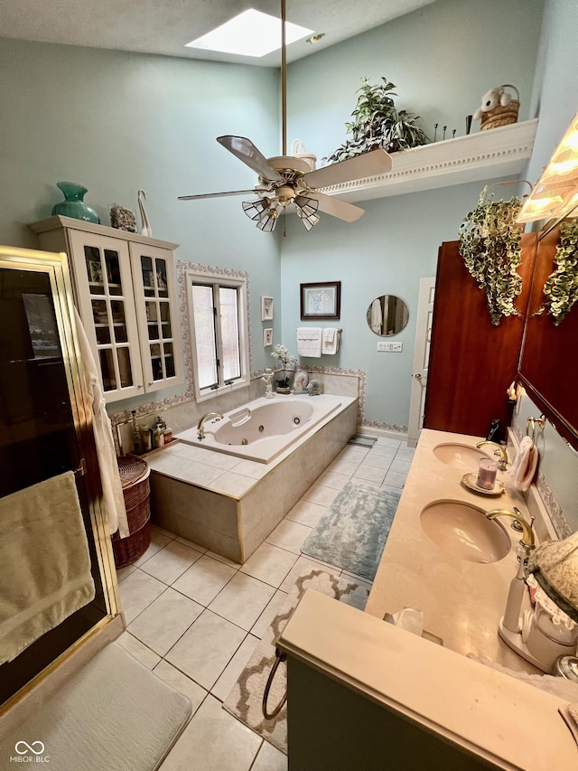 bathroom featuring tile patterned floors, tiled tub, a skylight, a towering ceiling, and ceiling fan