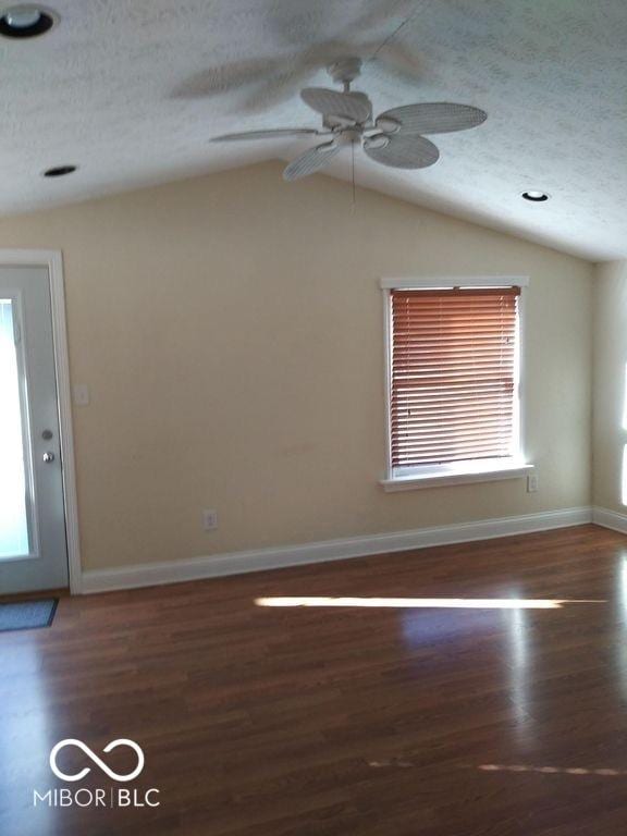 empty room featuring ceiling fan, vaulted ceiling, dark hardwood / wood-style floors, and a textured ceiling