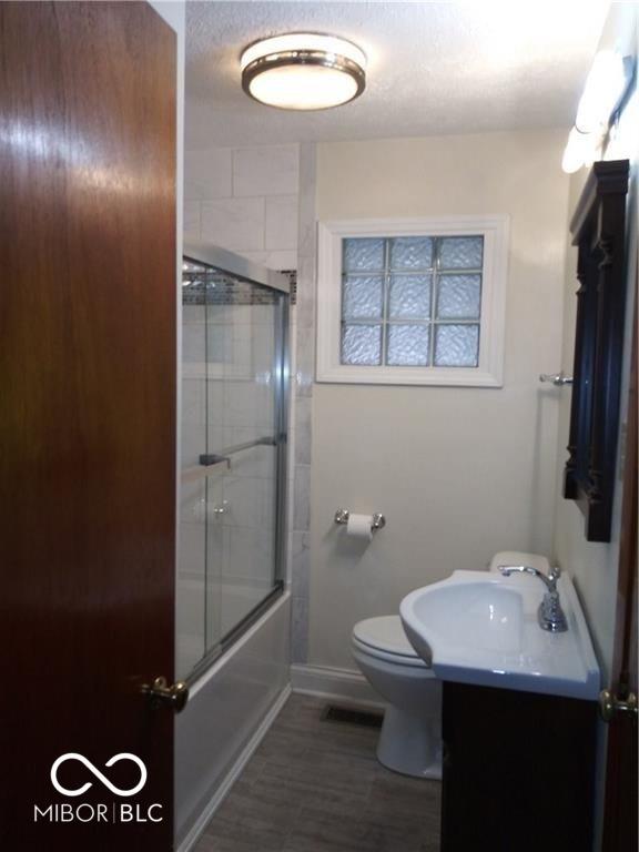 full bathroom featuring vanity, a textured ceiling, shower / bath combination with glass door, and toilet