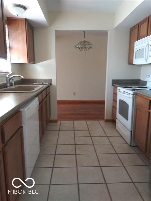 kitchen featuring pendant lighting, white appliances, sink, and light tile patterned floors