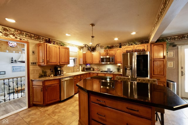 kitchen featuring appliances with stainless steel finishes, decorative light fixtures, a center island, and sink