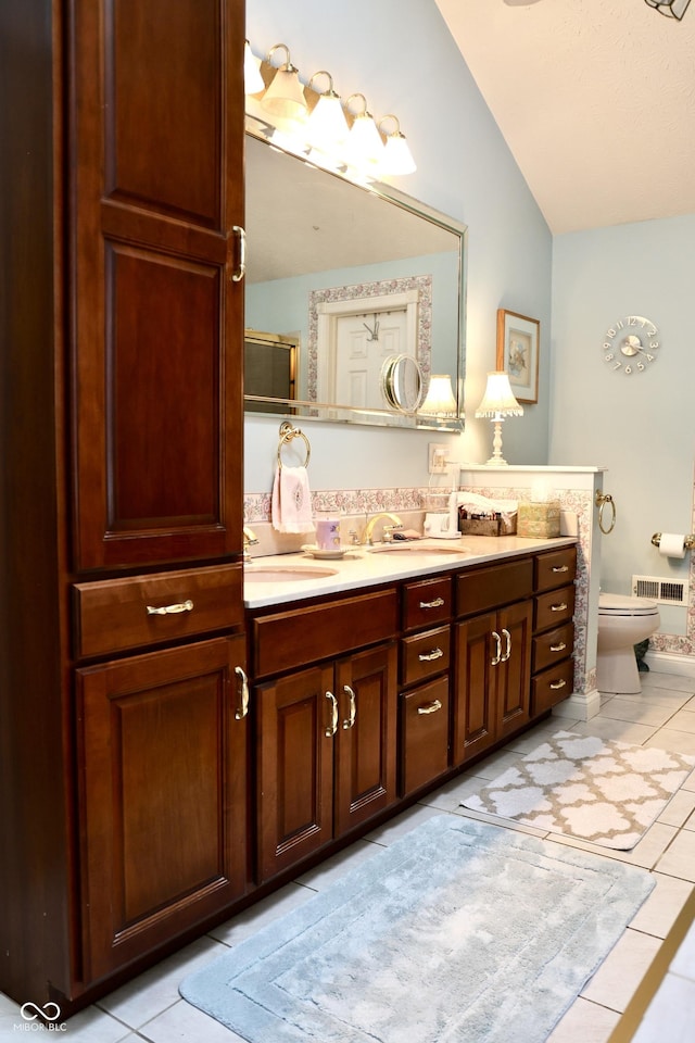 bathroom with tile patterned flooring, vaulted ceiling, vanity, and toilet