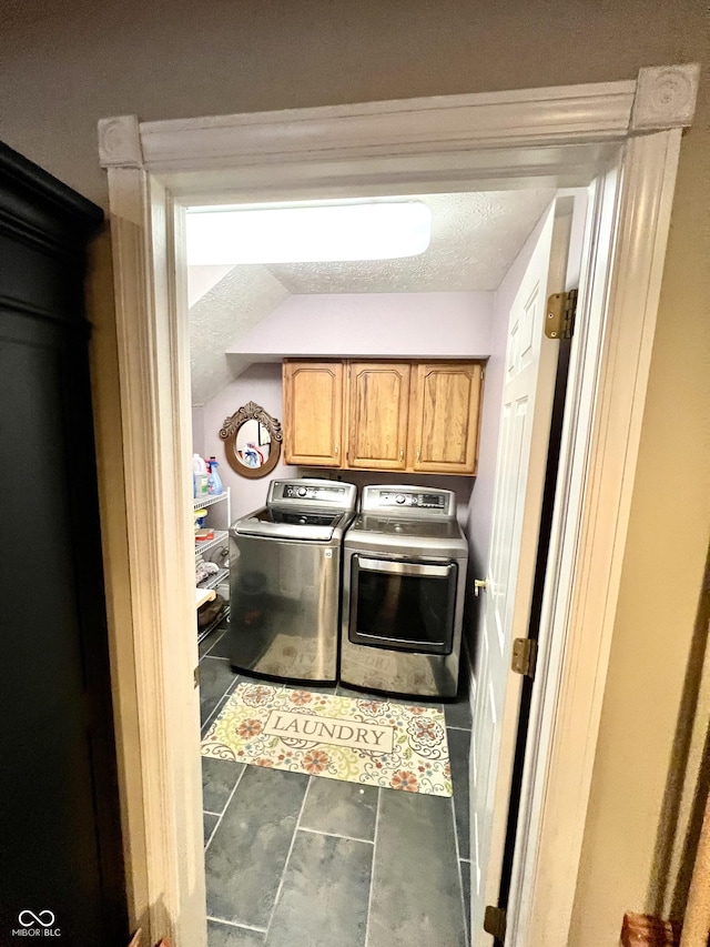 laundry room featuring cabinets, washer and clothes dryer, dark tile patterned flooring, and a textured ceiling