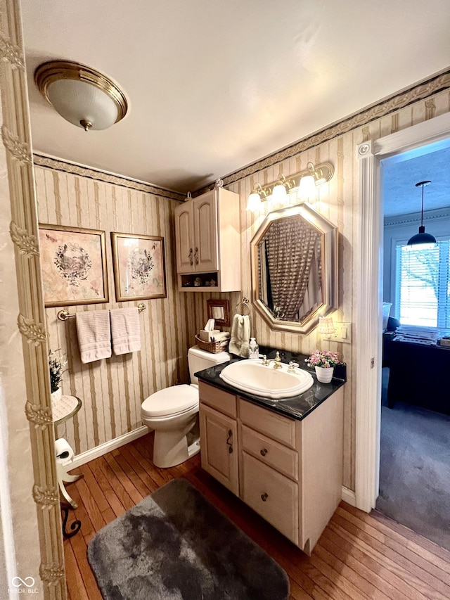 bathroom featuring hardwood / wood-style flooring, wooden walls, vanity, and toilet