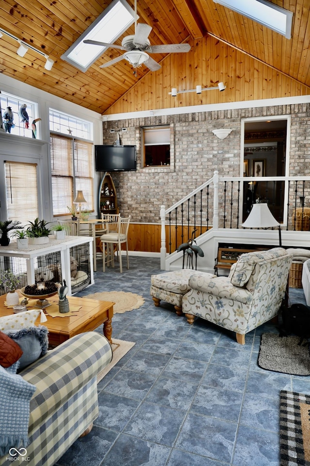 living room featuring ceiling fan, brick wall, lofted ceiling with skylight, and wooden ceiling