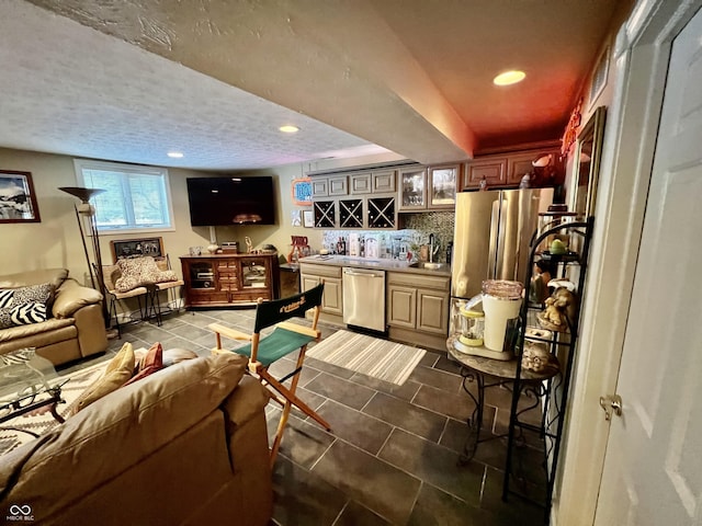 kitchen with appliances with stainless steel finishes, sink, backsplash, dark tile patterned flooring, and a textured ceiling