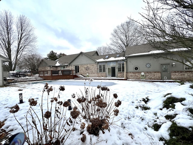 snow covered back of property with a wooden deck