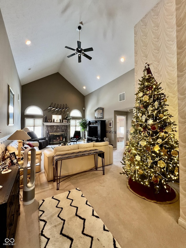 carpeted living room featuring ceiling fan, a high end fireplace, and high vaulted ceiling