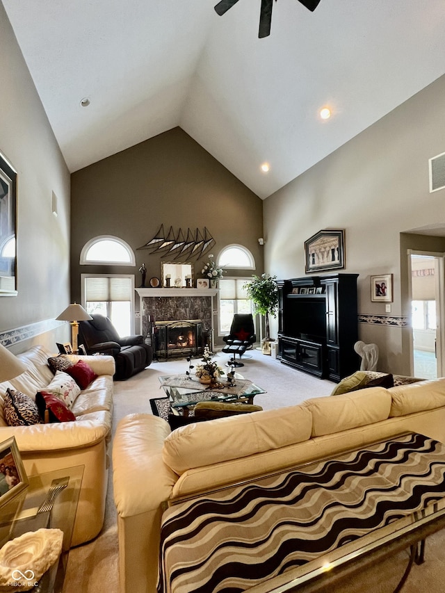 carpeted living room with a premium fireplace, ceiling fan, and high vaulted ceiling