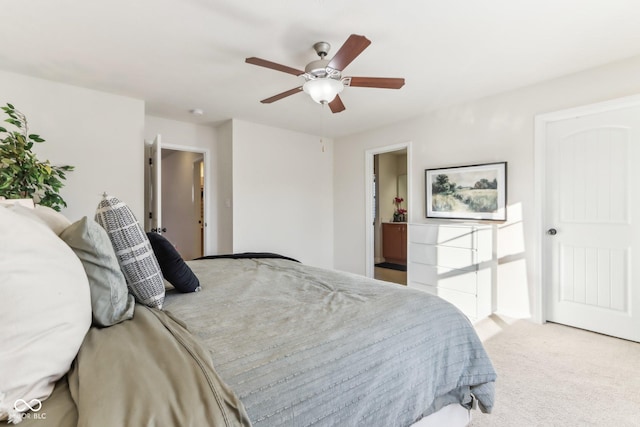 bedroom with ensuite bath, ceiling fan, and light carpet